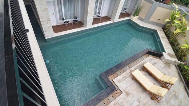 A swimming pool with lounge chairs and a covered seating area. - Griya Sunset Kuta (Kuta)