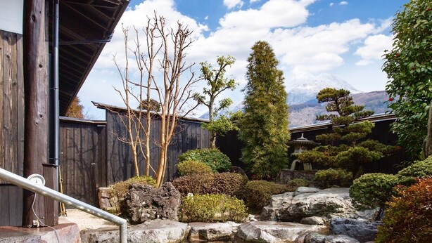 Een traditionele Japanse tuin met een helder vijver, rotsen en verschillende bomen.