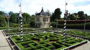 Un jardin labyrinthique avec un kiosque central et des poteaux rayés.
