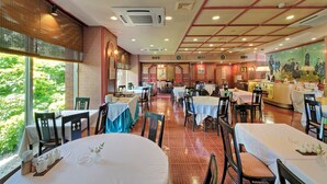 A restaurant with multiple tables and chairs, a counter, and a mural on the wall. - Akita Park Hotel (Akita)