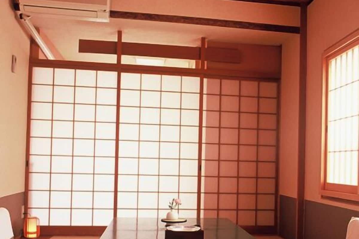 Ein traditioneller japanischer Raum mit Tatami-Bodenbelag, einem niedrigen Tisch und einem Shoji-Schirm.