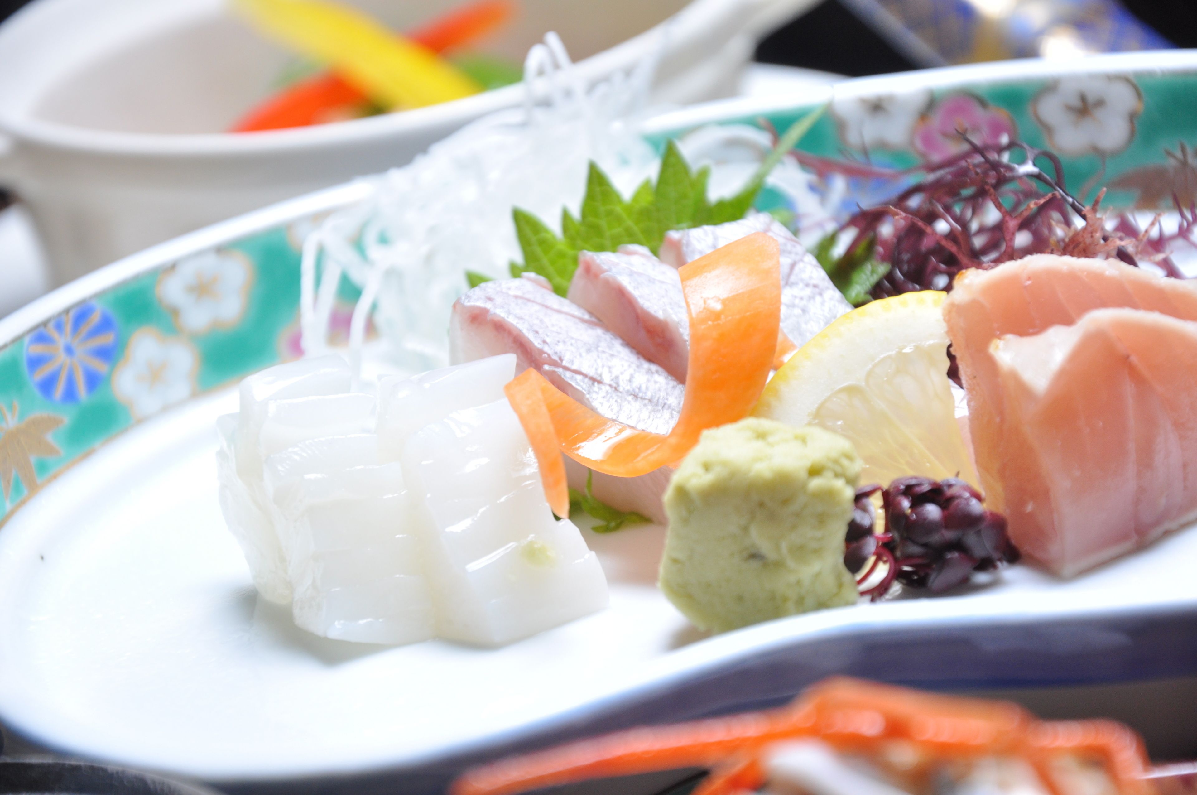 Un plato de sashimi con distintos tipos de pescado y guarniciones.