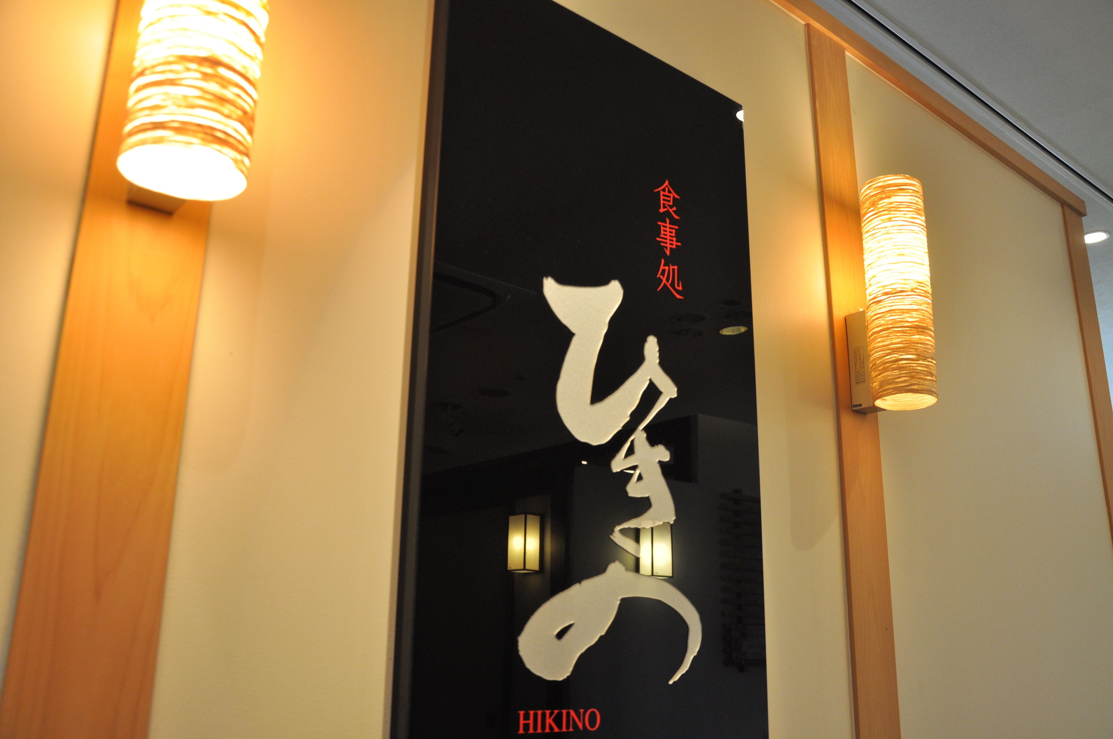 Ein Schild mit japanischen Schriftzeichen und dem Wort 'HIKINO' in Rot.