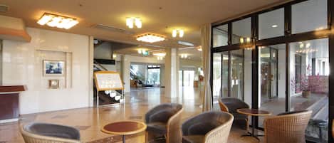 A lobby with wicker chairs, a reception desk, and a large glass door leading outside.