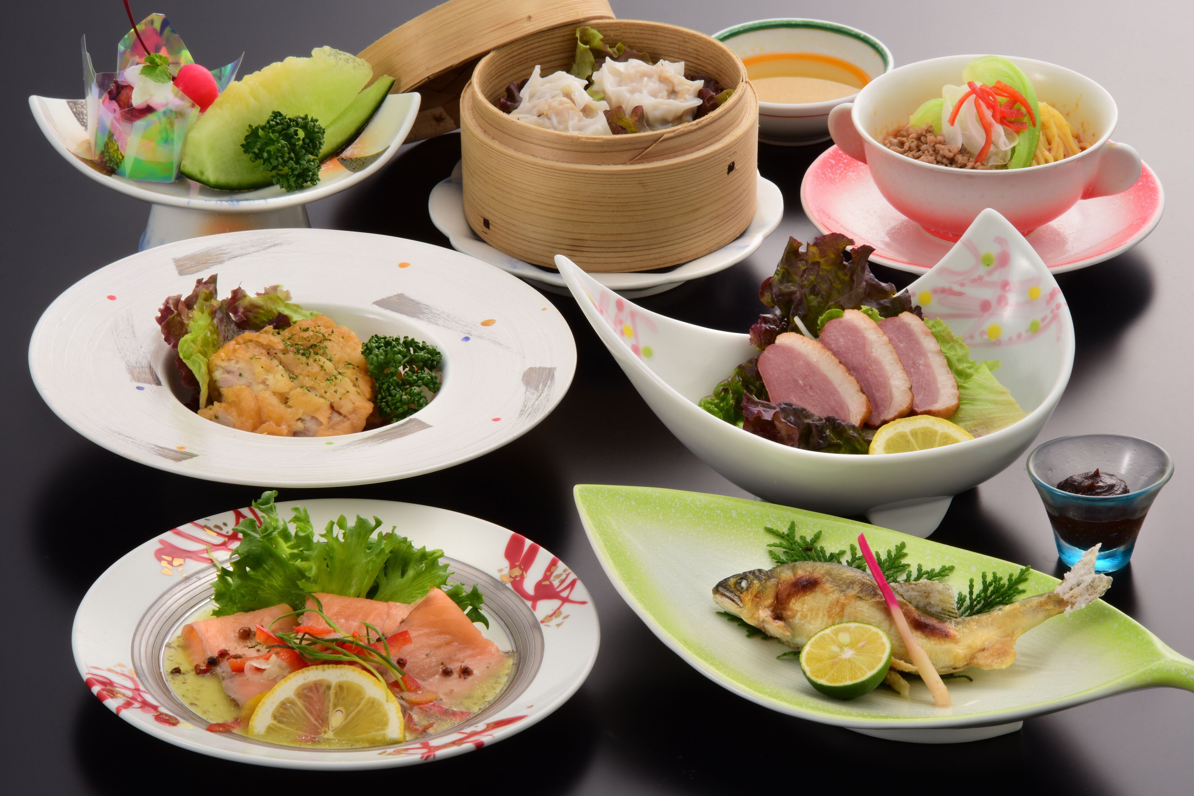 Diverse gerechten, waaronder sushi, sashimi en een gestoomd gerecht, gepresenteerd op een tafel.