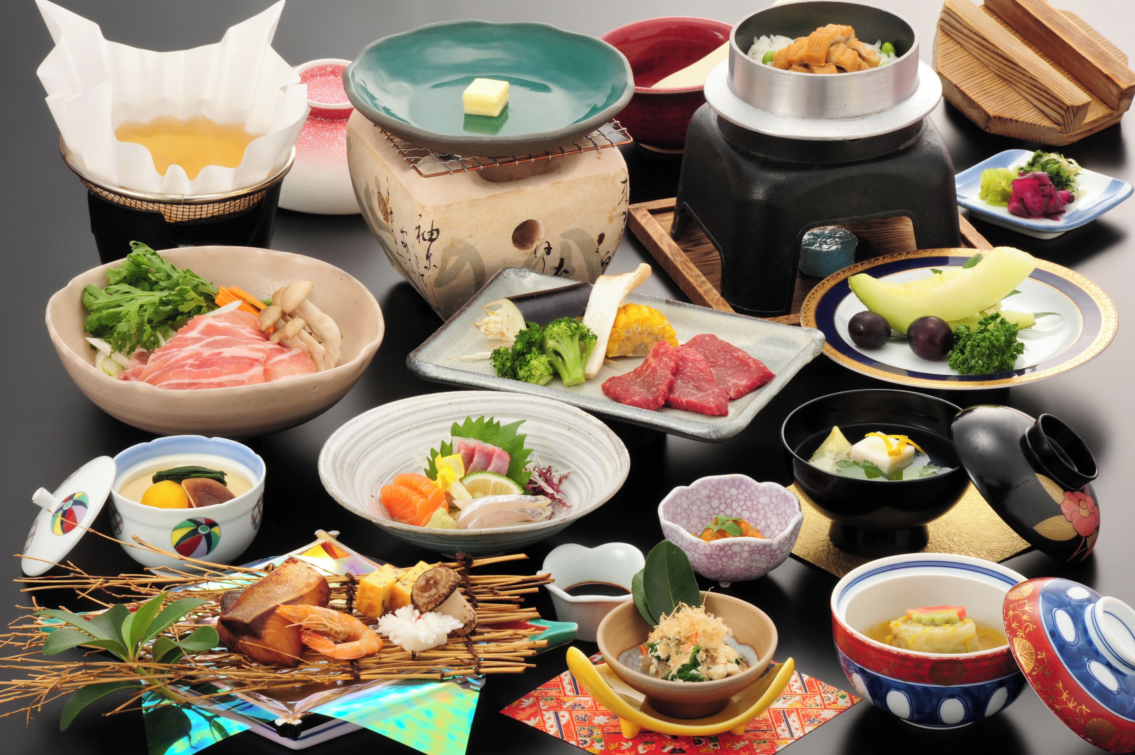 A variety of Japanese dishes and hot pots on a table.