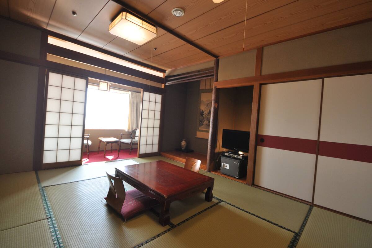 Ett traditionellt japanskt rum med tatamimattor på golvet, ett lågt träbord och skjutdörrar.