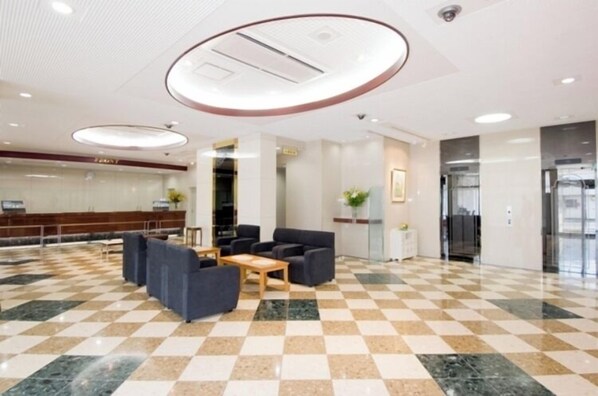 A hotel lobby with a checkered floor, seating area, and a reception desk.