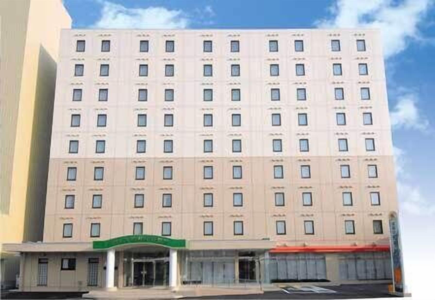 A multi-story hotel with a symmetrical facade, evenly spaced windows, and a central entrance with a green awning.