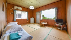 A room with a bed, a small table, a TV, and a window with curtains. - Pension Hoshi NO Suna (Taketomi)