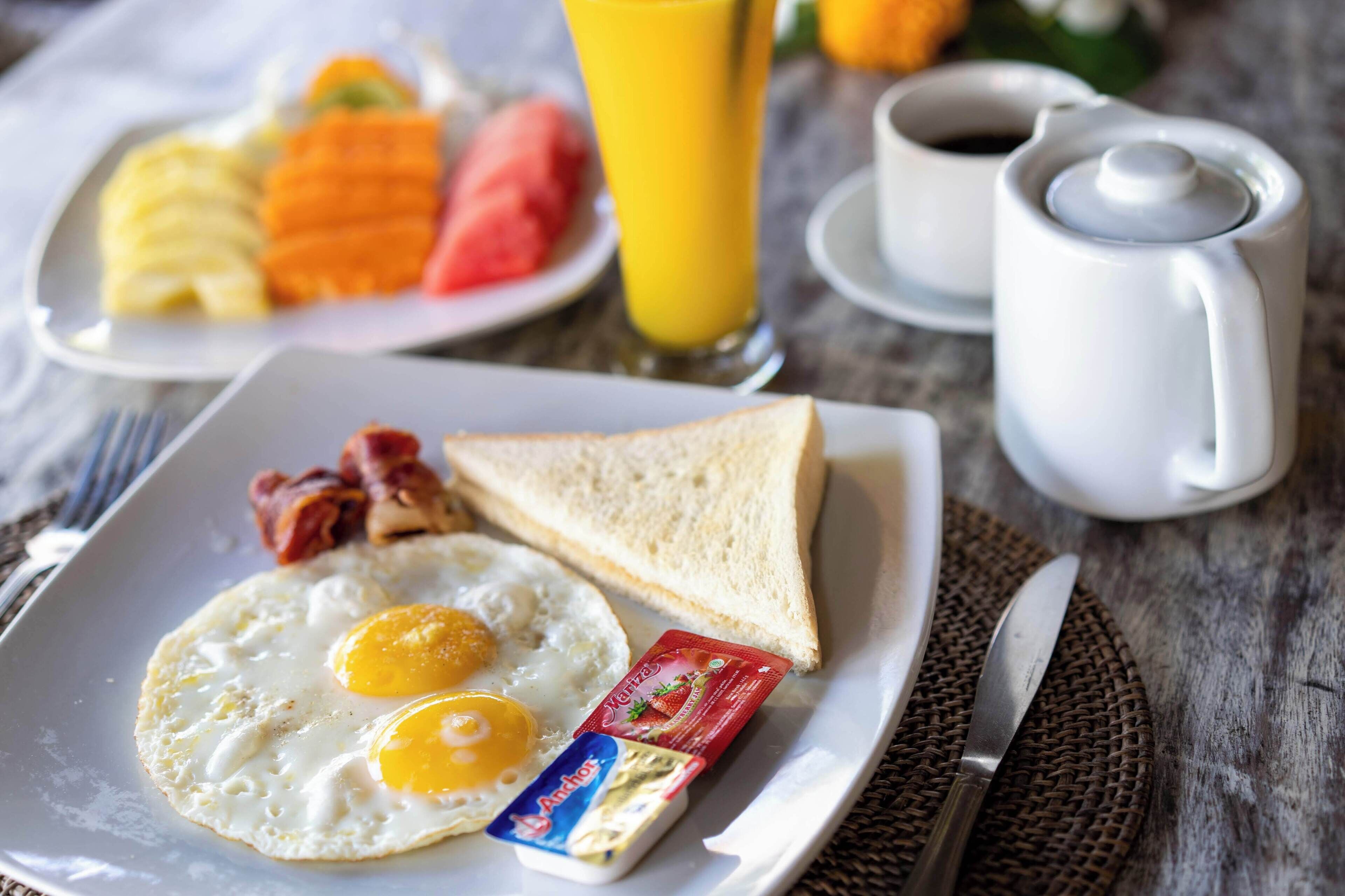 Un plato de desayuno con huevos, tocino, tostadas y mermelada.