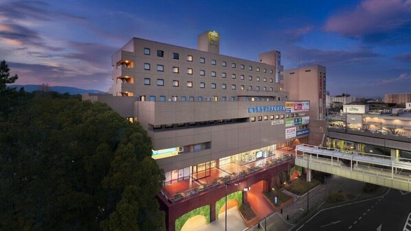 A multi-story hotel with a modern design, featuring a prominent entrance and a rooftop terrace.