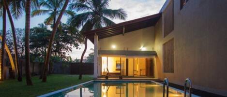 Una piscina al aire libre, sillones reclinables de piscina