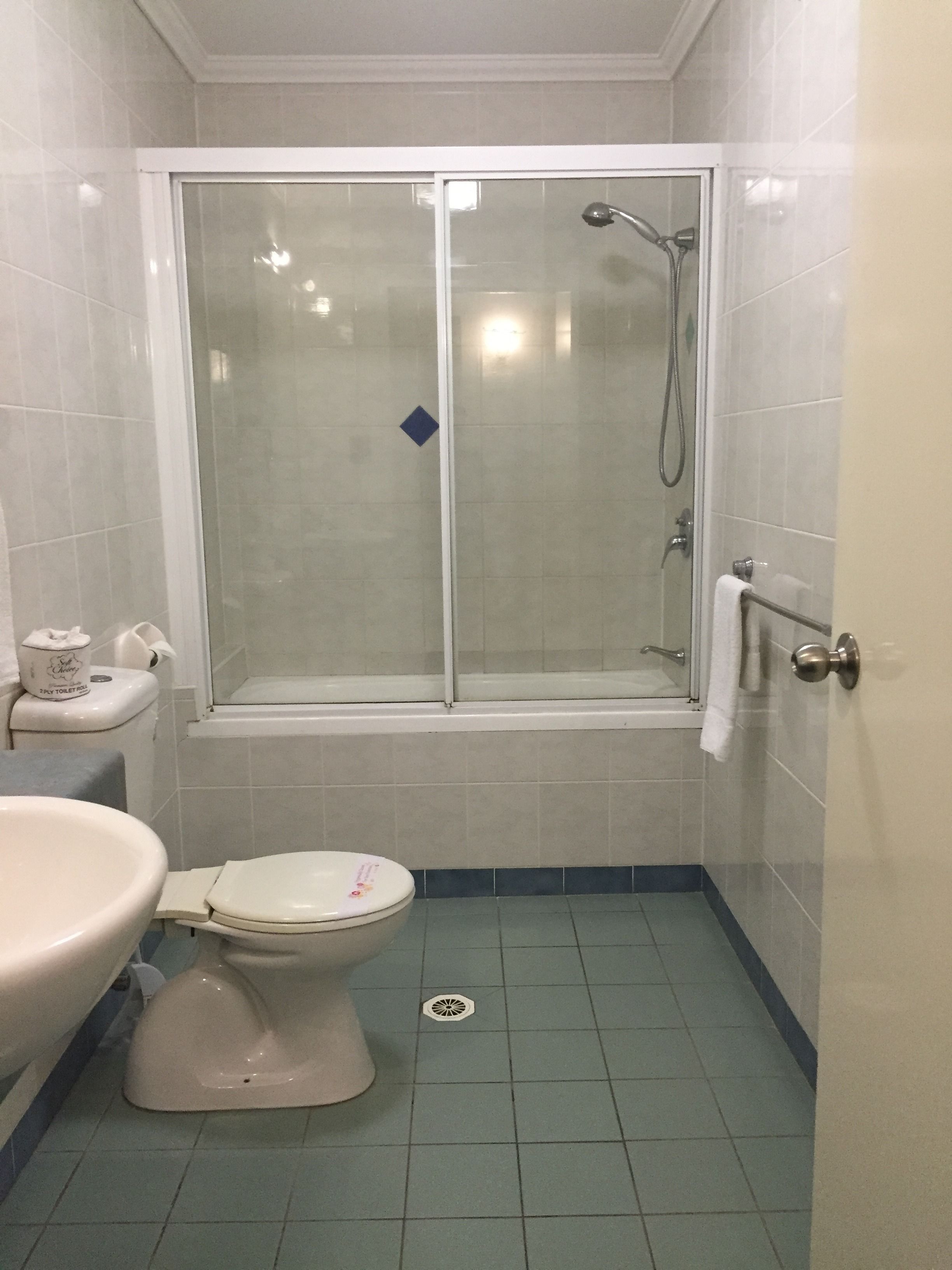 A bathroom with a toilet, sink, and shower stall.