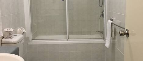 Un baño con inodoro, lavamanos y cabina de ducha.