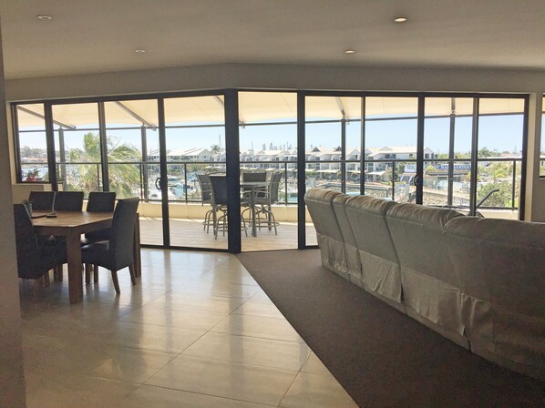 A spacious room with a dining area, a sofa, and a view of a marina.