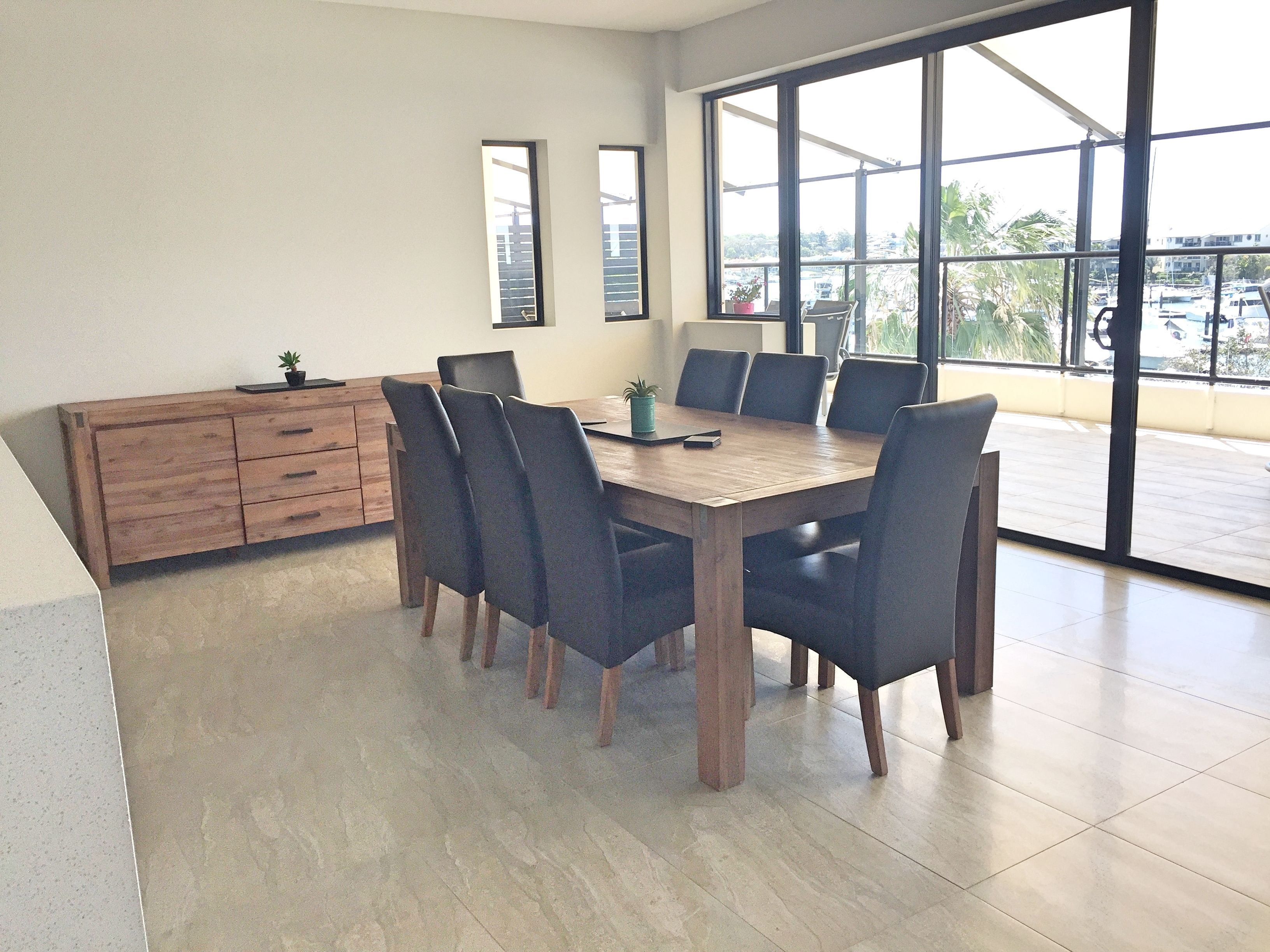 Un amplio comedor con una mesa y sillas de madera, ventanas grandes y vistas al exterior.