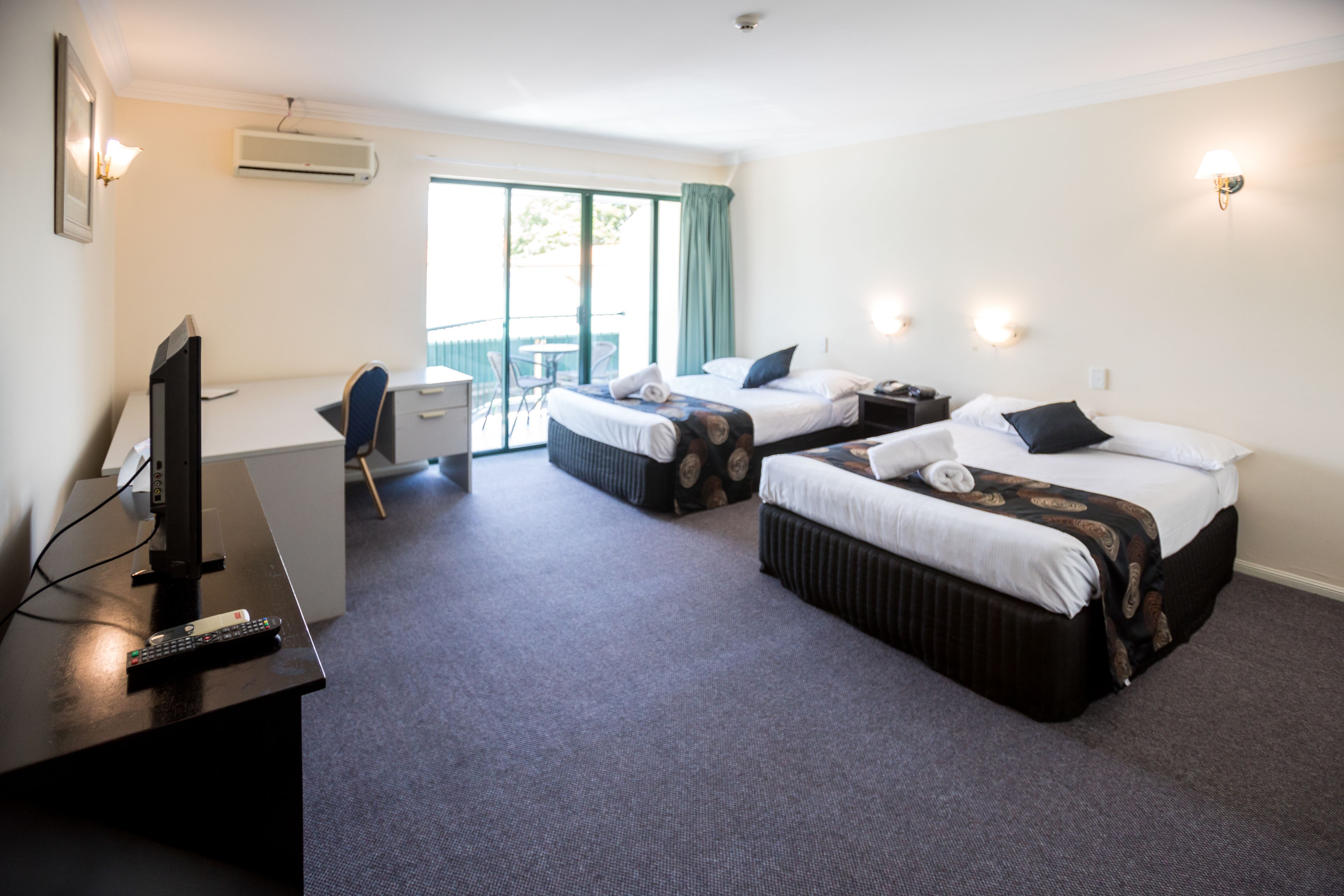 A hotel room with two beds, a desk with a computer, a TV, and a chair.