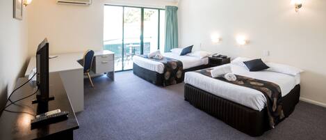 A hotel room with two beds, a desk with a computer, a TV, and a chair.