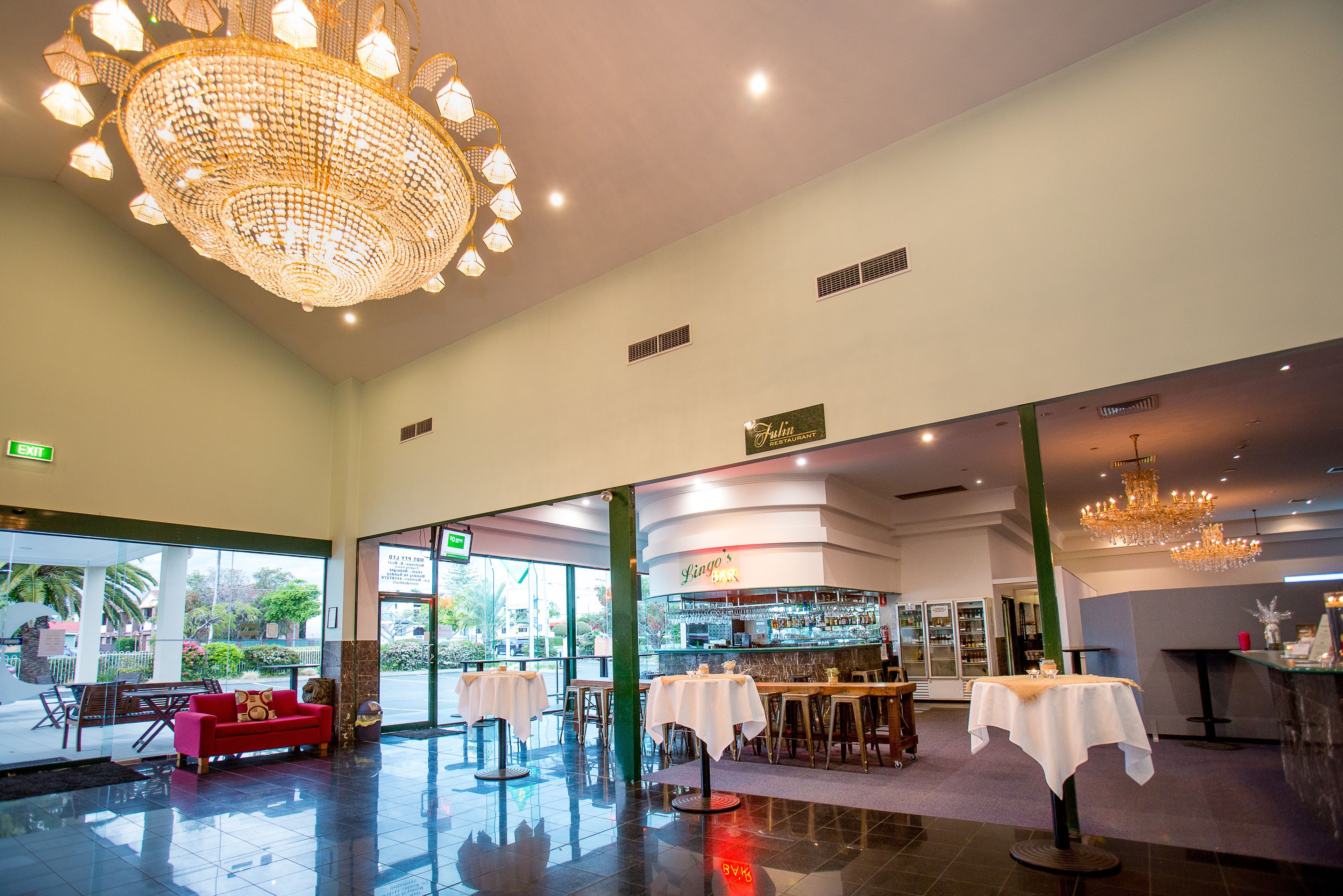 A spacious lobby with a bar area, a red sofa, and a chandelier.