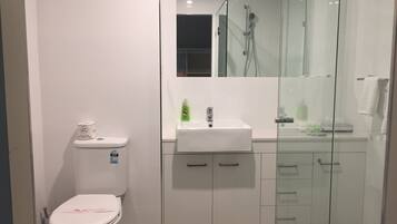 A modern bathroom with a toilet, a sink, and a glass-enclosed shower.