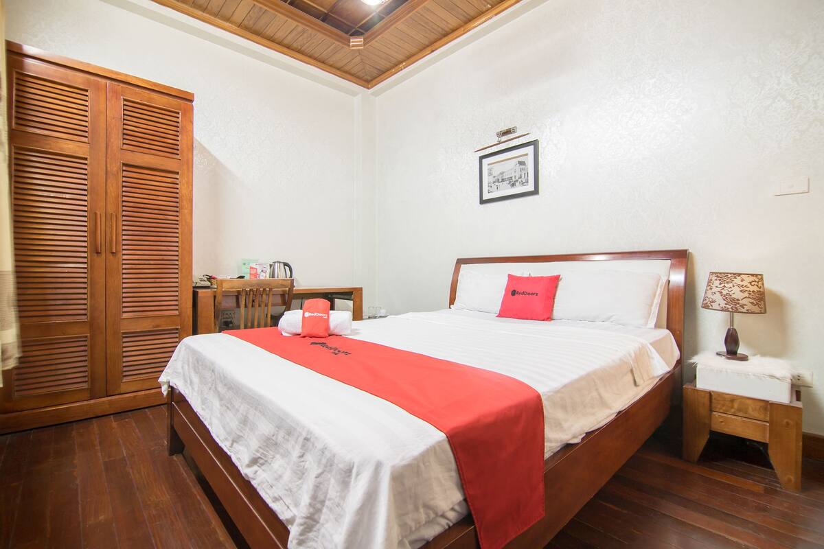 Un dormitorio ordenado con cama, mesita de noche, lámpara y armario.