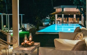 An outdoor pool area with lounge chairs and a table with candles. - W15 Escape (Ahangama)