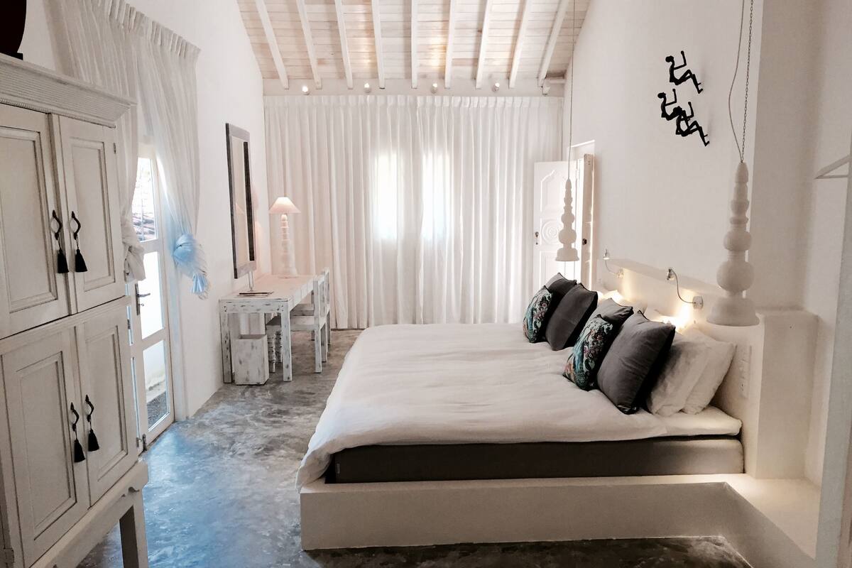Un dormitorio con una cama grande, un escritorio y un armario.