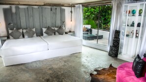 A modern bedroom with a white sofa bed, a leather pouf, and a glass coffee table. - W15 Escape (Ahangama)