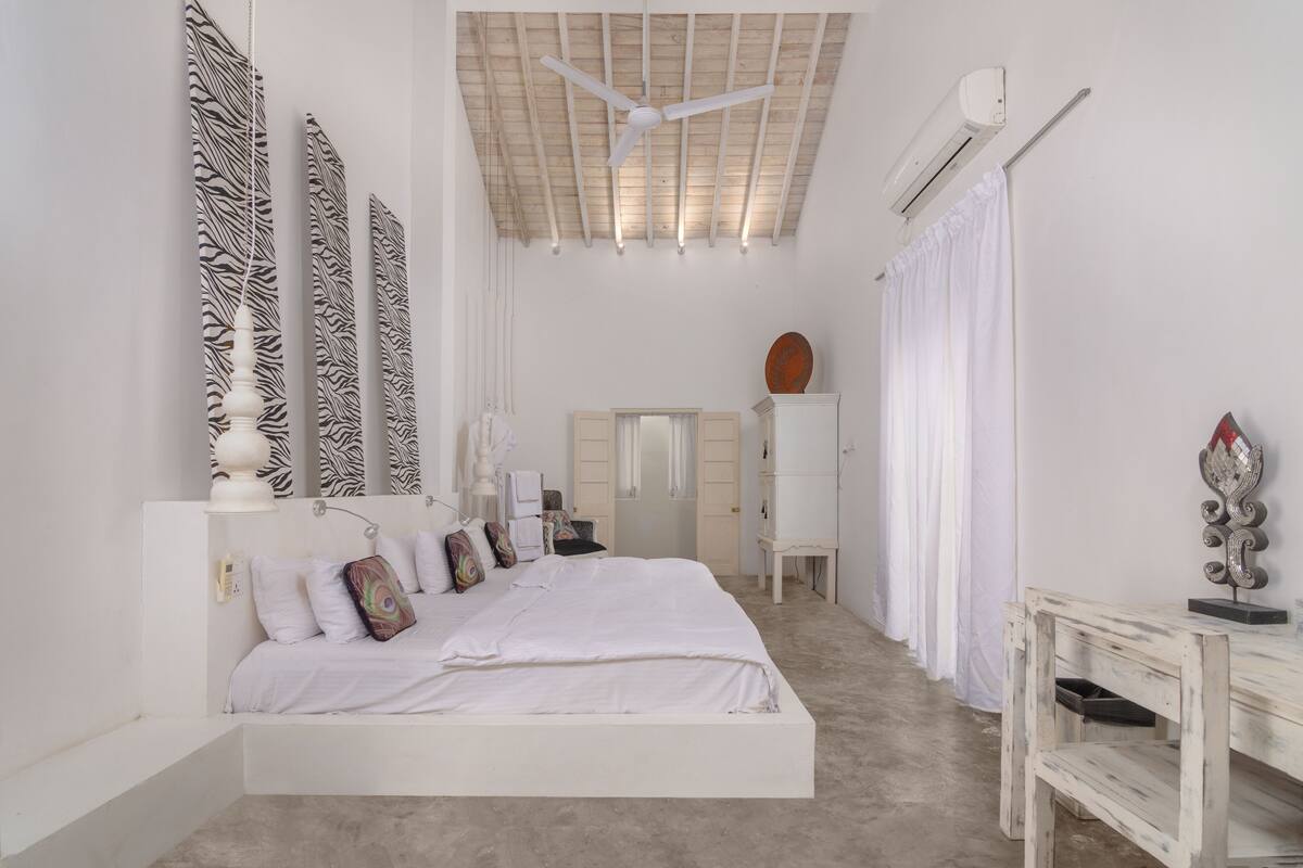 Un dormitorio con cama, escritorio, armario y ventilador de techo.
