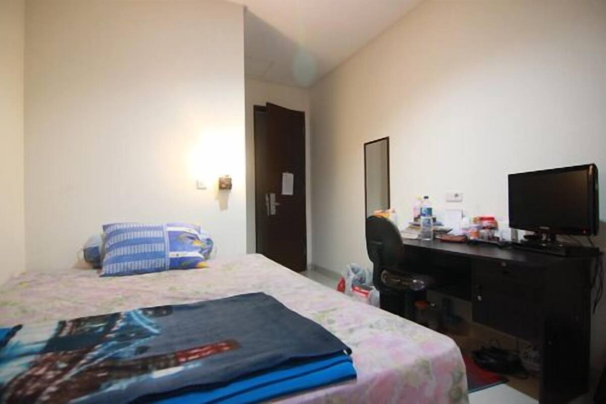A hotel room with a bed, a desk with a computer, a chair, and a TV.