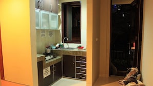 Una cocina compacta con un lavamanos, armarios y una ventana.