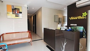 Una zona de recepción con un mostrador, un banco y un equipo de aire acondicionado de pared.