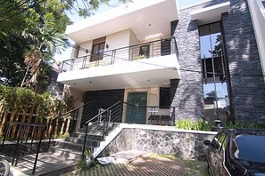 A two-story building with a balcony, a staircase leading to the entrance, and a stone facade. - Griya Amartha (Jakarta)