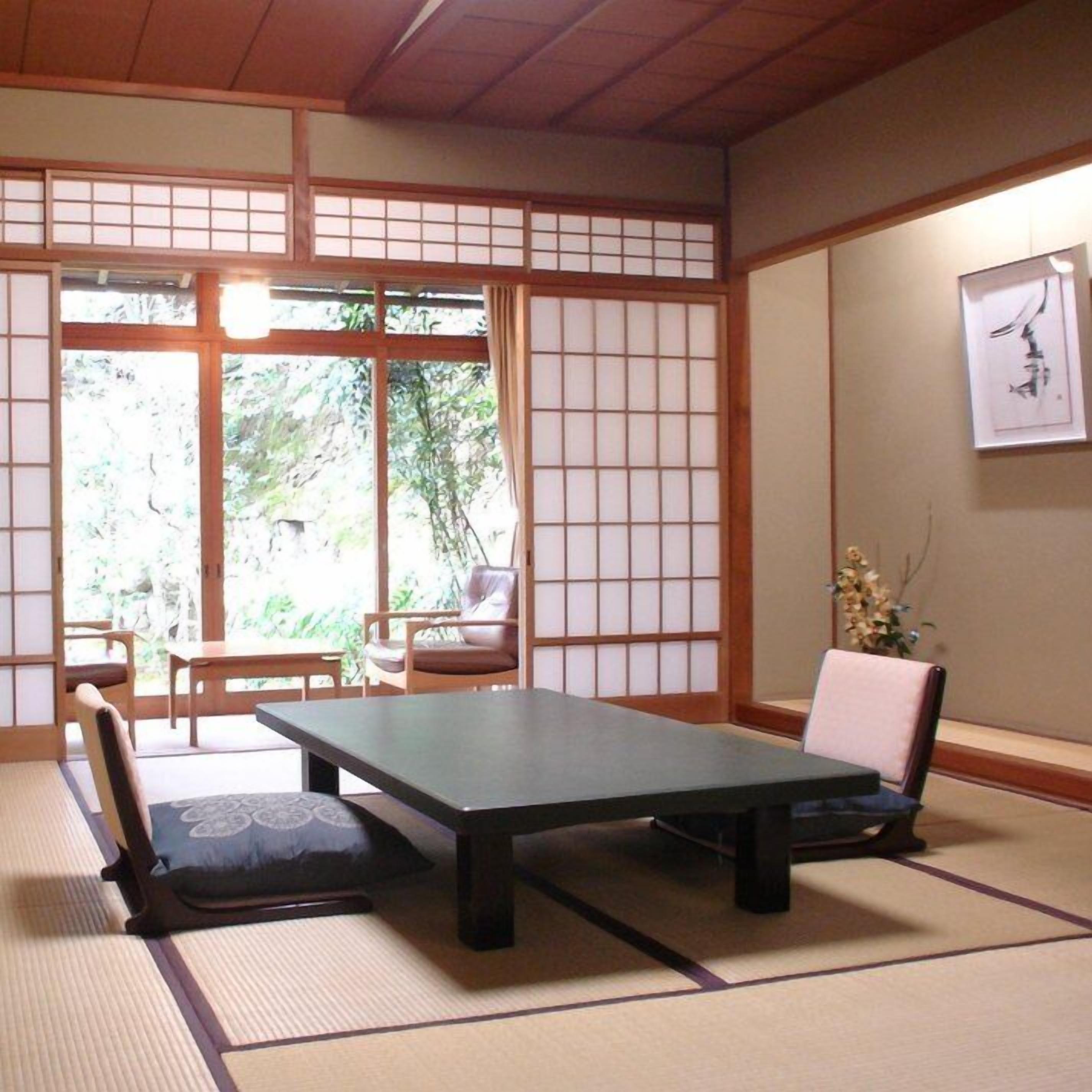 Una habitación japonesa tradicional con suelo de tatami, una mesa baja y puertas correderas.