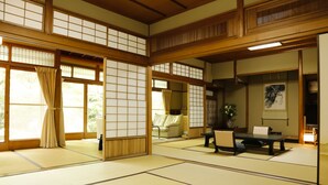 A traditional Japanese room with tatami flooring, sliding doors, and a low table with cushions. - Hashinoya Annex Ransui (Kobe)