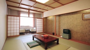 Una habitación japonesa tradicional con suelo de tatami, una mesa de madera baja, un televisor y una puerta corredera.