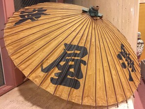 A traditional Japanese umbrella with black calligraphy. - Hotel Sawaya (Hokota)