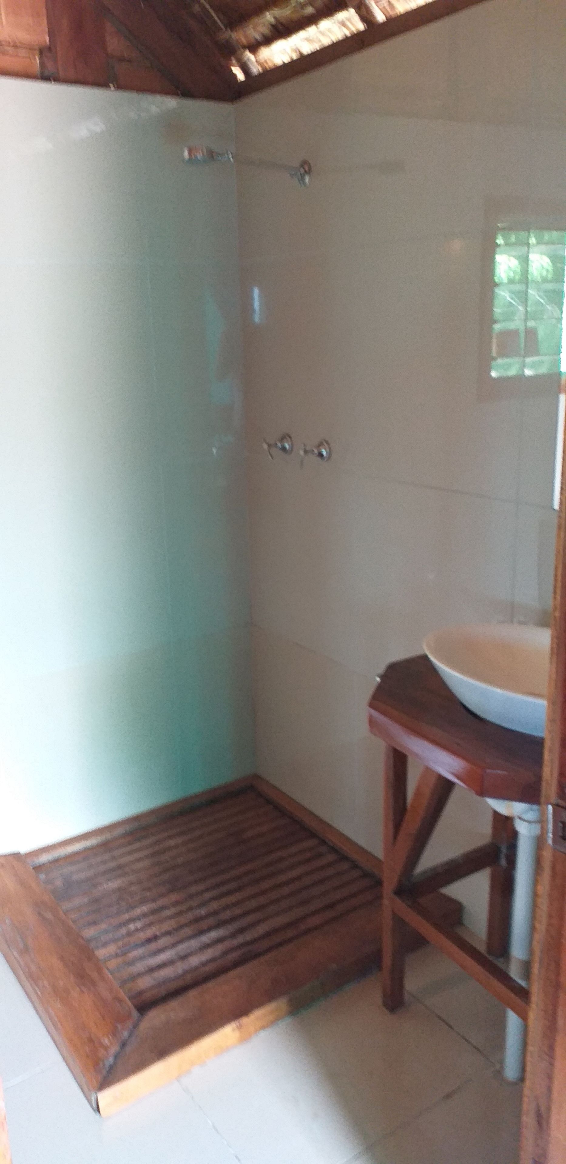 Un baño con ducha, un banco de madera y un lavabo.