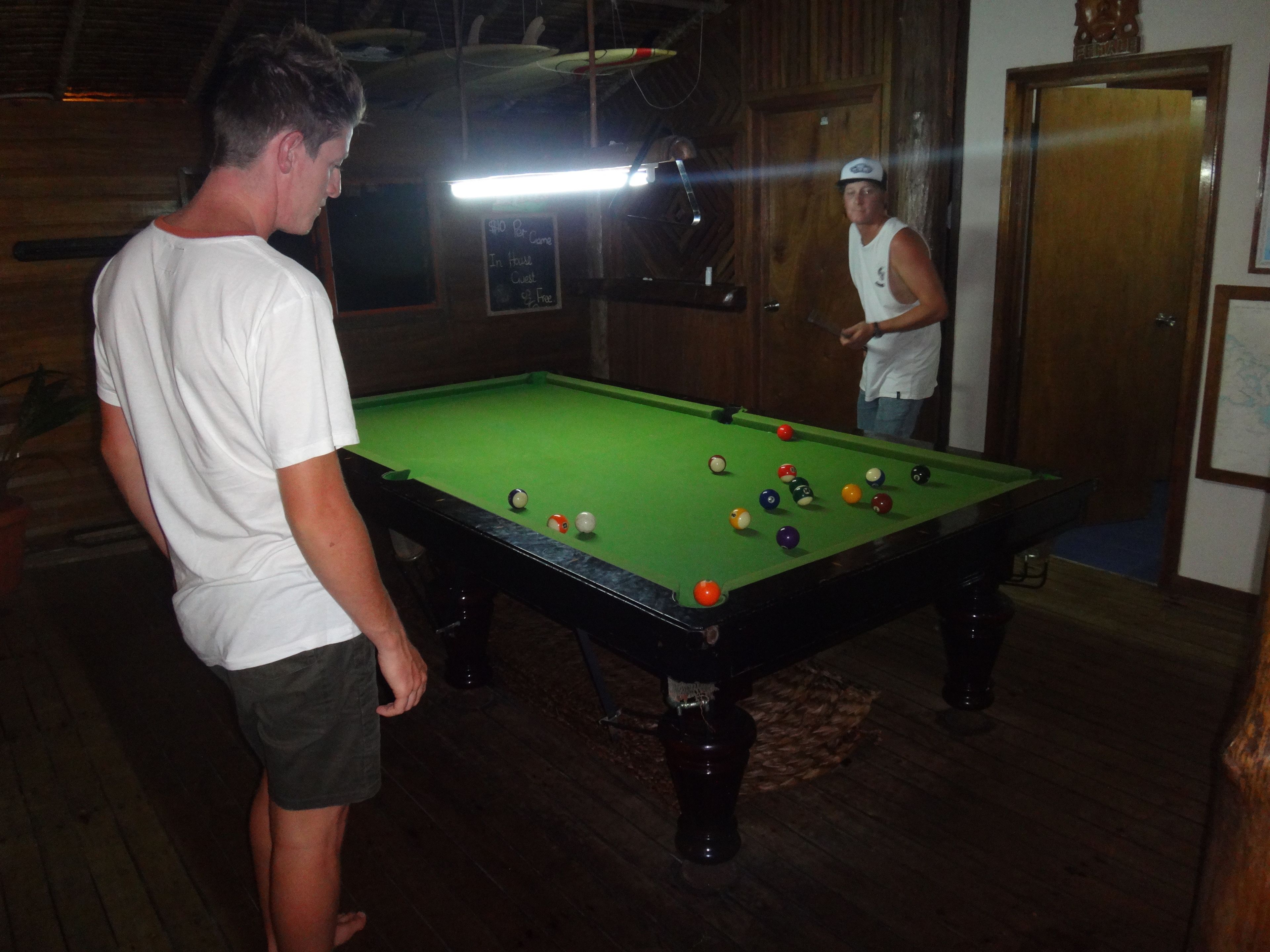 Ein Billardtisch mit Kugeln, eine Tafel mit Preisen und Holzwände.