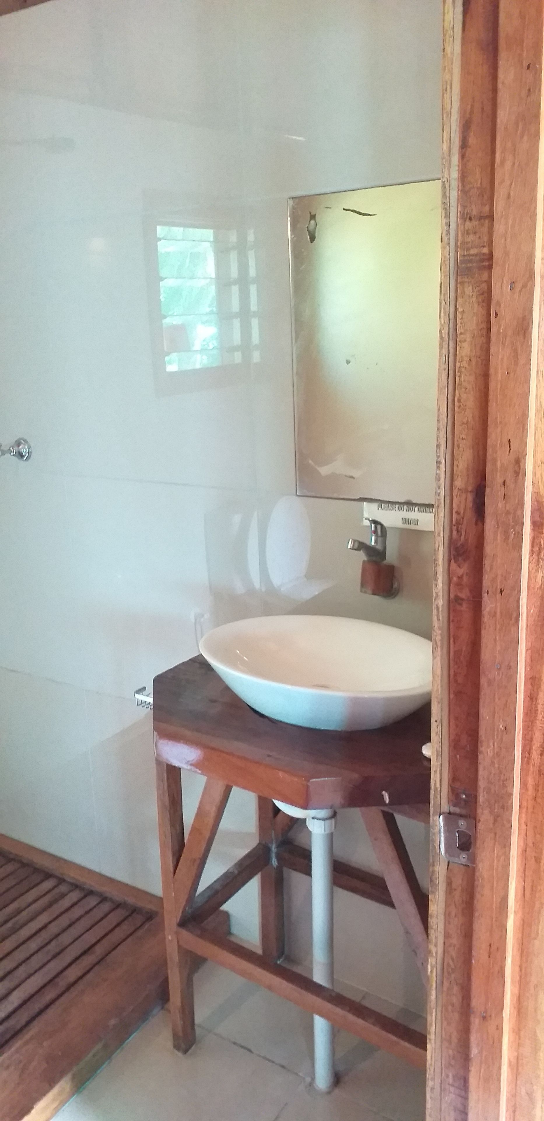 A bathroom with a wooden vanity, a white sink, and a mirror.