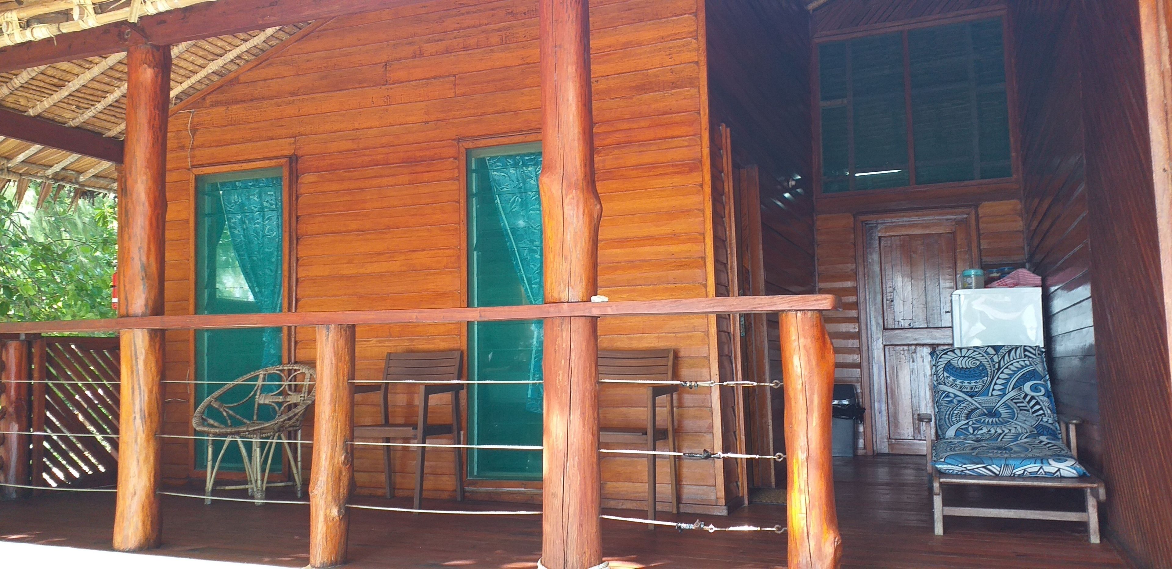 A wooden cabin with a porch, two doors, and a chair.