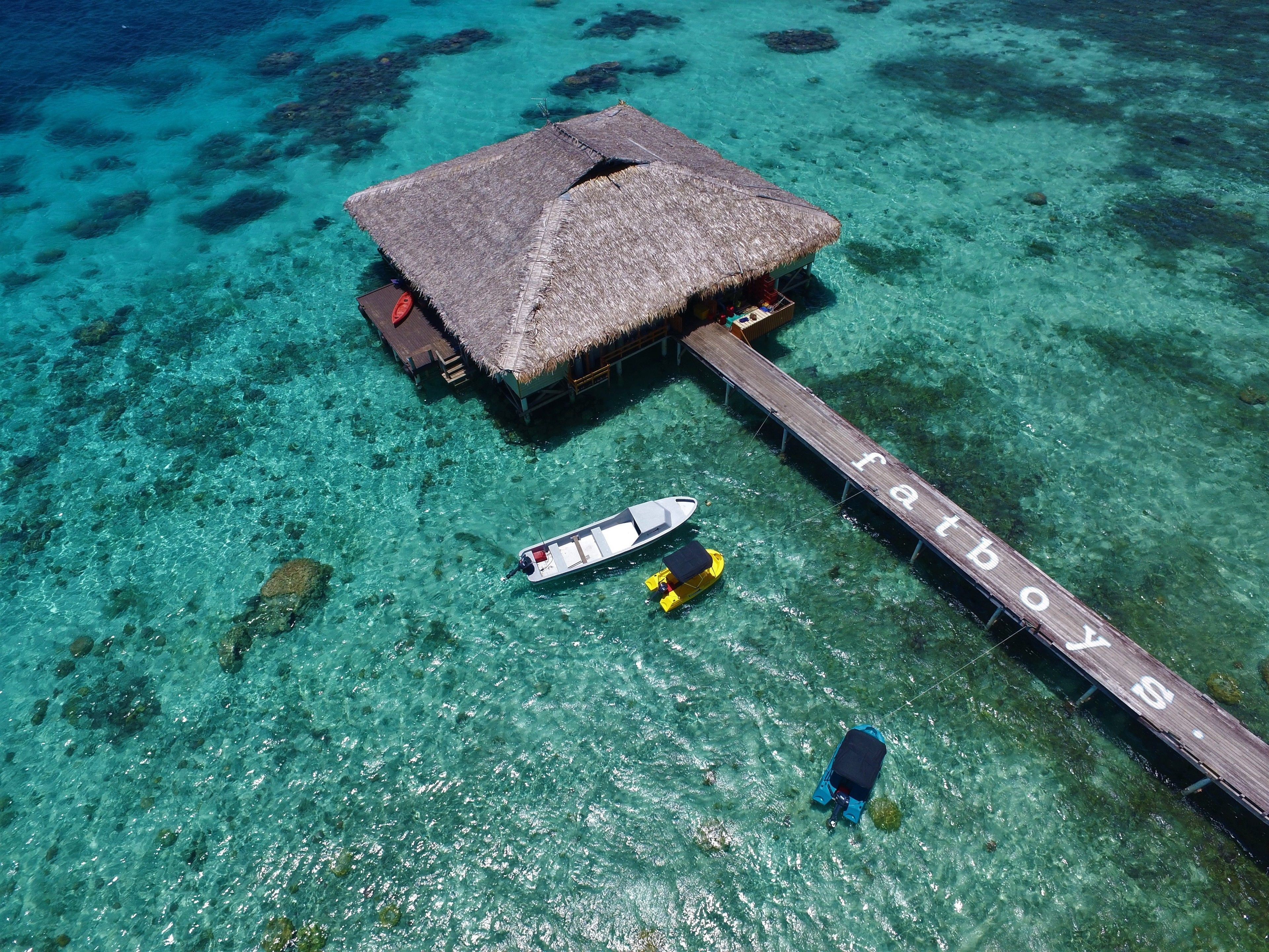 An overwater bungalow with a thatched roof, a dock, and clear turquoise water.