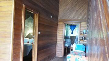 A wooden interior with a bed, a table, and a bench.