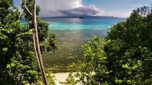 A tropical beach with clear turquoise waters, a sailboat, and lush greenery. - Fatboys Resort (Mbambanga Island)