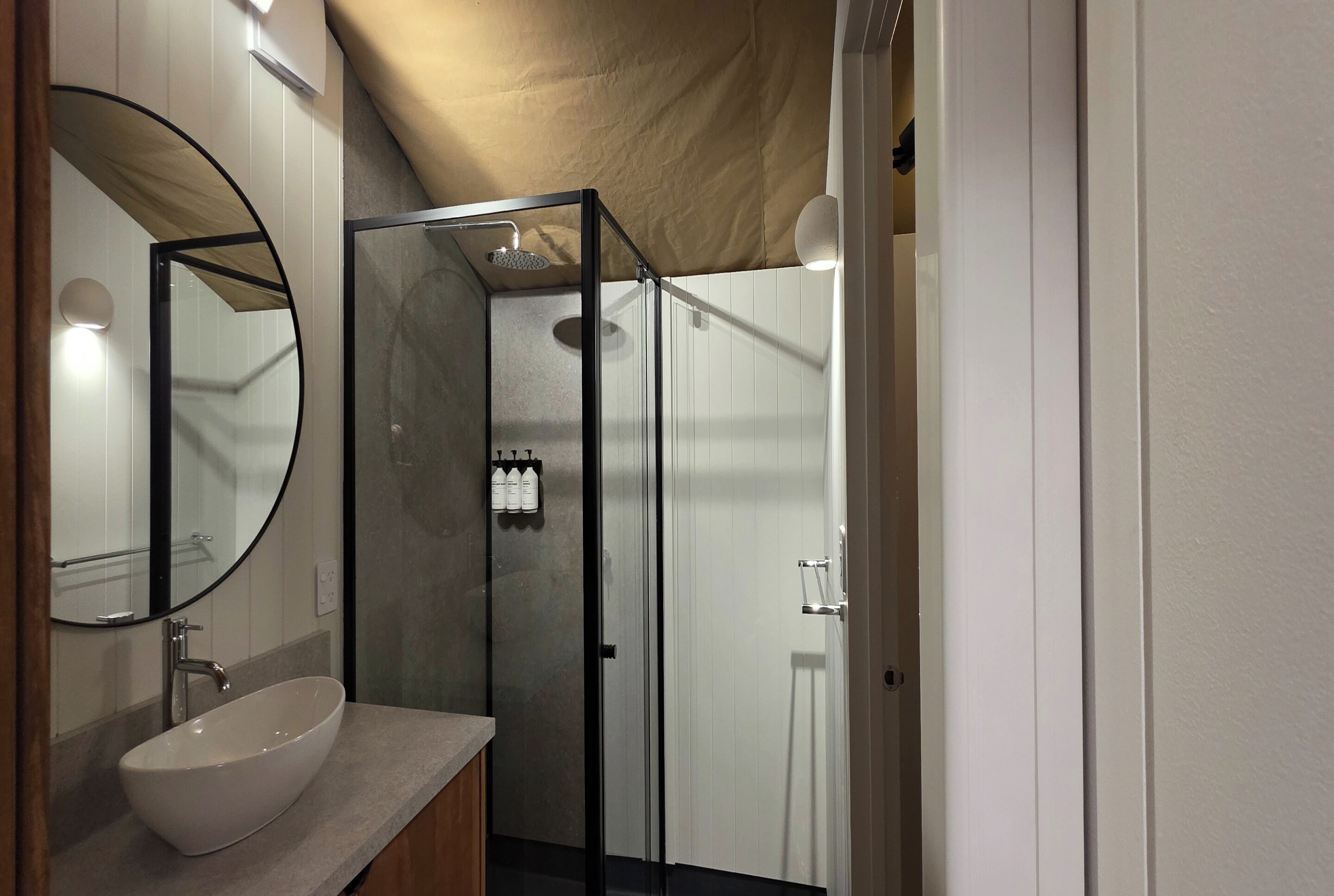 A modern bathroom with a glass-enclosed shower, a white sink, and a mirror.