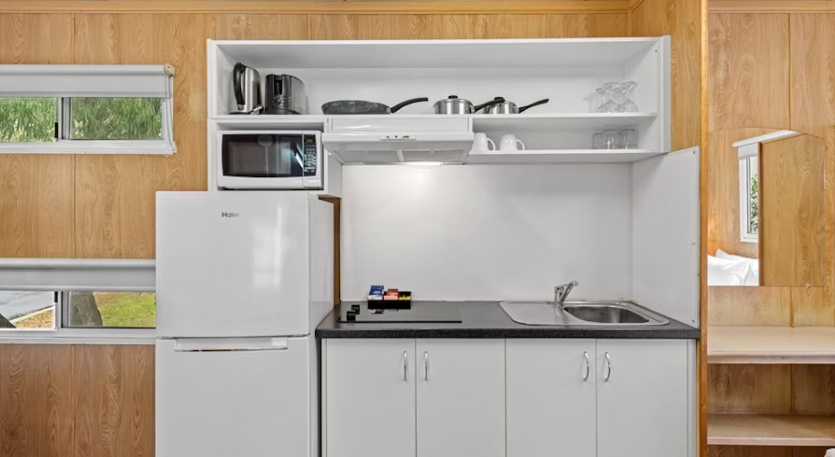A compact kitchen with a refrigerator, microwave, and sink.