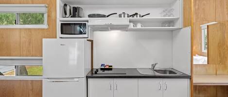 A compact kitchen with a refrigerator, microwave, and sink.
