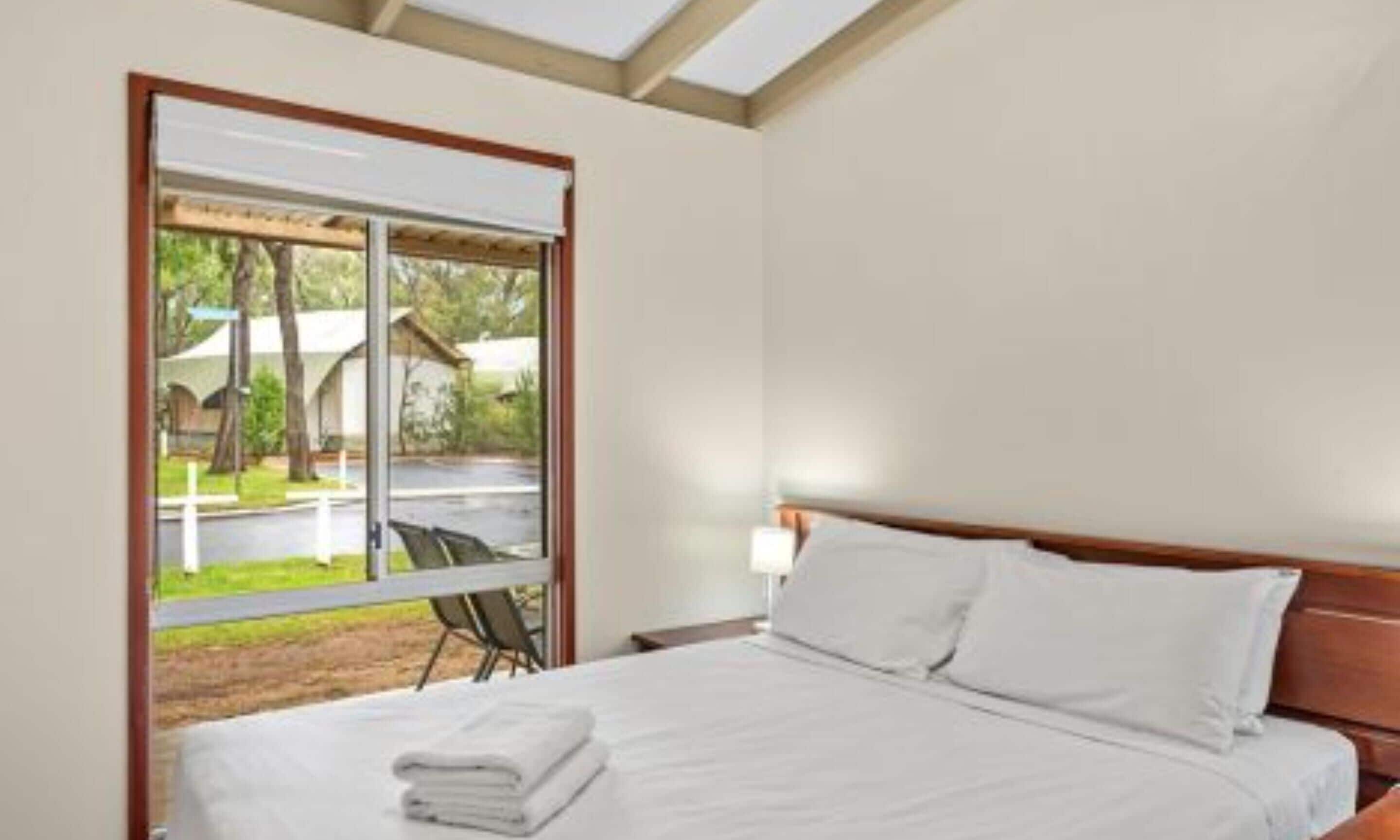 Habitación de hotel con una cama grande, una ventana con vistas al exterior y un cabecero de madera.
