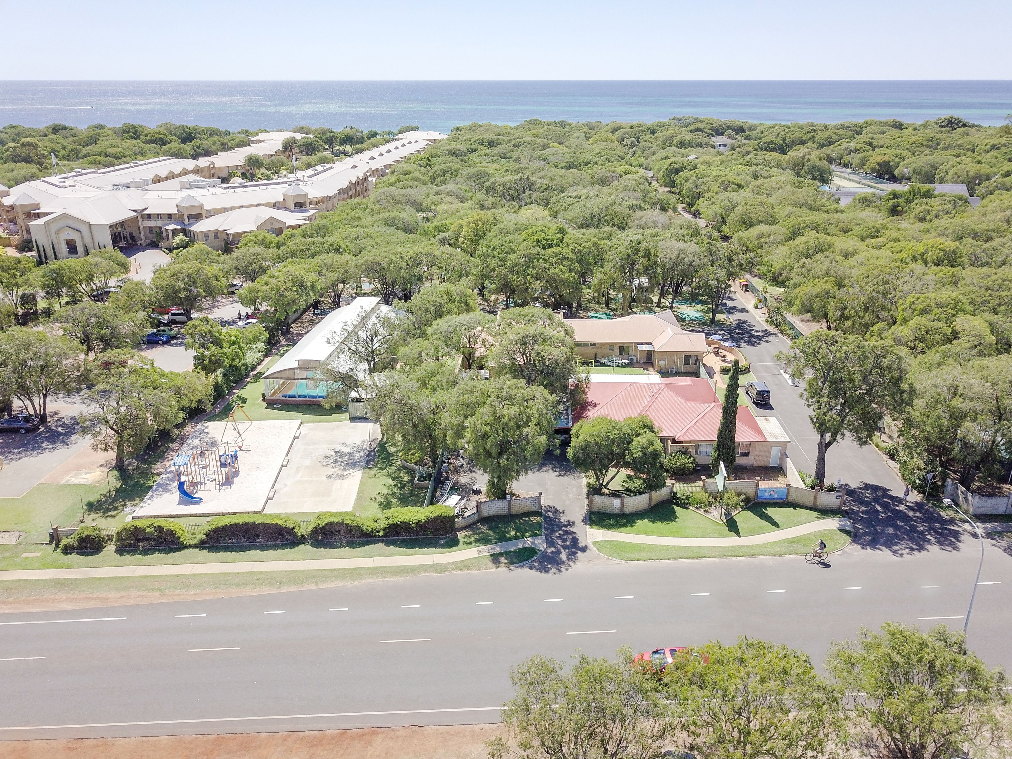 An aerial view of a residential area with houses, a playground, and a road.